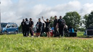 Menschen stehen mit gepackten Sachen auf einem Campingplatz. © NDR Foto: Dominik Dührsen