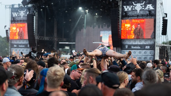 Ein Mann wird von der Menge vor einer Konzertbühne getragen. © NDR Foto: Dominik Dührsen