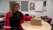 Eine junge Frau wirft einen Zettel in eine Box. © NDR 