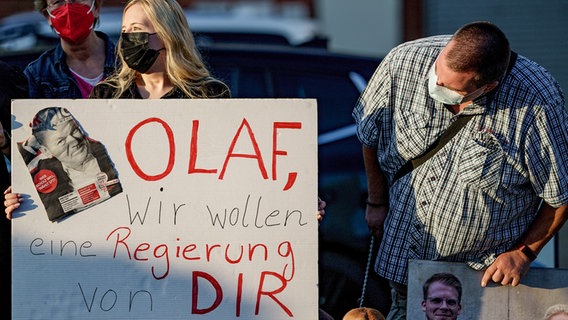 Anhänger von Olaf Scholz halten vor der ARD-Wahlarena zur Bundestagswahl in der Kulturwerft Gollan ein Plakat mit der Aufschrift «Olaf, wir wollen eine Regierung von Dir» in den Händen. © picture alliance/dpa Foto: Axel Heimken