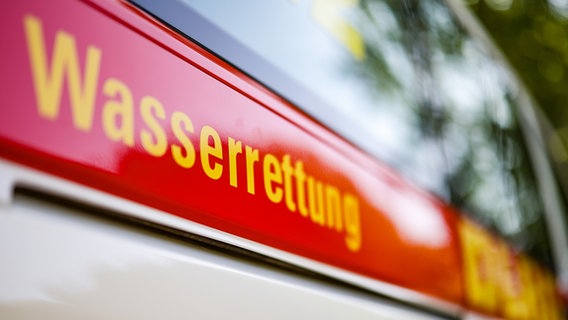 Ein roter Streifen mit dem Schriftzug Wasserrettung DLRG ist an einem Einsatzfahrzeug zu sehen. © picture alliance/dpa Foto: Christoph Reichwein