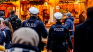 Polizisten gehen über den Weihnachtsmarkt in der Kieler Innenstadt. © Axel Heimken/dpa 