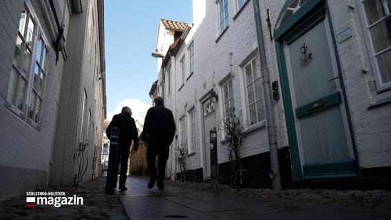 Zwei Männer laufen eine enge Wonhhausgasse entlang. © NDR 