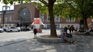 Vor dem Hauptbahnhof Kiel sitzen viele Menschen, die kein Obdach zu haben scheinen. © NDR Foto: Anne Passow