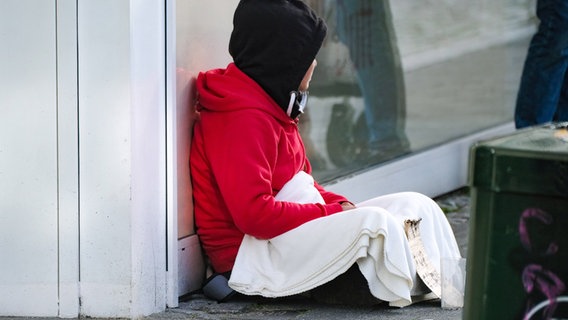 Eine obdachlose Person sitzt auf der Straße. © IMAGO Foto: Michael Gstettenbauer