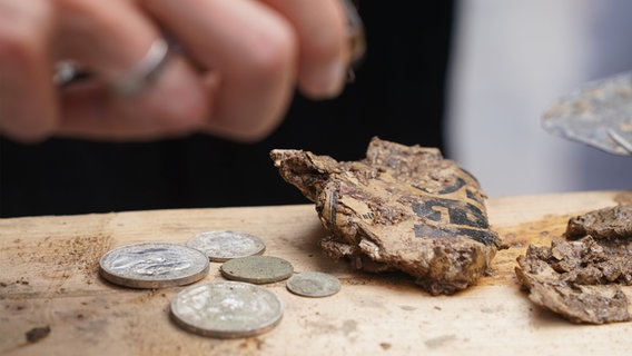 Eutin: Münzen und eine vermoderte und feuchte Zeitung liegen nach der Öffnung neben einer Zeitkapsel. © dpa-Bildfunk Foto: Marcus Brandt