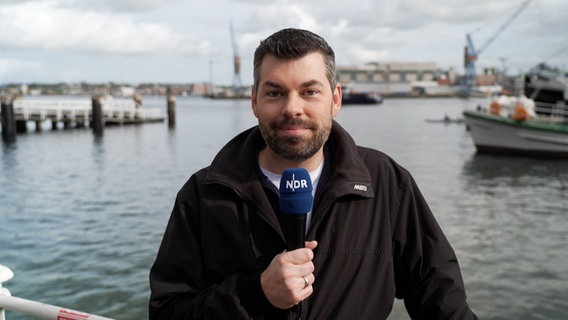 NDR Moderator Sebastian Wache steht an der Kieler Förde mit der Wettervorhersage. © NDR 