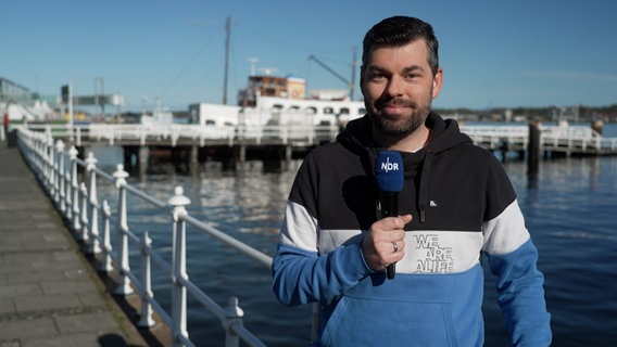 NDR Moderator Sebastian Wache steht an der Kieler Förde mit der Wettervorhersage. © NDR 