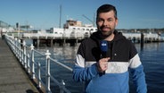 NDR Moderator Sebastian Wache steht an der Kieler Förde mit der Wettervorhersage. © NDR 