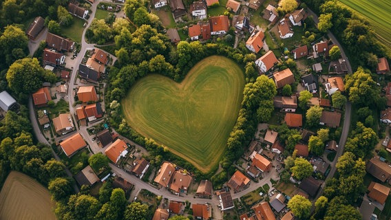 Ein KI-generiertes Bild, dass ein Dorf von oben in Herzform zeigt. © NDR / KI generiert mit Midjourney 