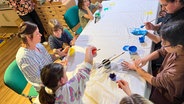 Corinna Fischer macht Handabdrücke mit Kindern, deren Eltern an Krebs erkrankt sind oder waren. © NDR Foto: Anna Koerber