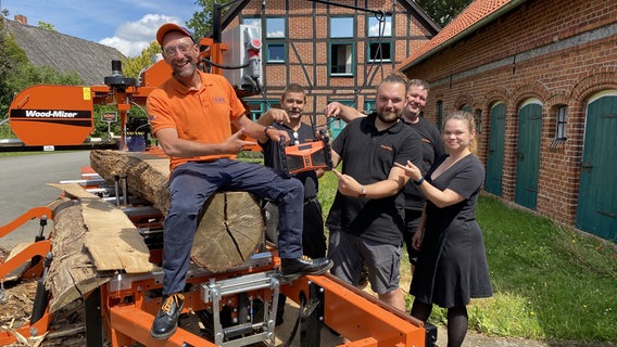 Schorse übergibt ein Dabbi DAB+ Radio an Robin Prüß und das Team des mobilen Sägewerks Wood Mizer. © NDR Foto: Bernd Drechsler