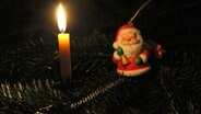 Eine Kerze und ein Weihnachtsmann an einem Tannenbaum © NDR Foto: Simone Timpe