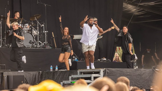 Ray Dalton tanzt im weißen Shirt auf der Bühne, umgeben von Tänzern und Band © NDR 2 Foto: Axel Herzig