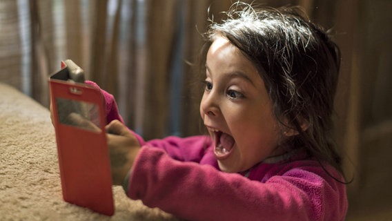 Ein kleines Kind spielt begeistert mit einem Smartphone. © imago stock&people 