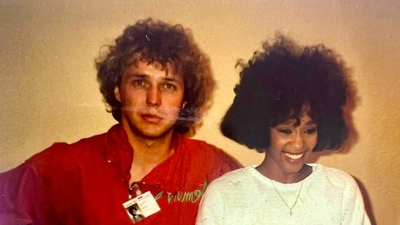 Uwe Bahn steht neben Whitney Houston im weißen Kleid, vermutlich beim Montreux Festival 1987. © NDR 2 