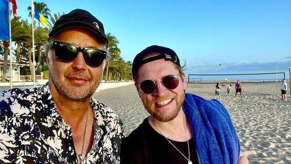 Uwe Bahn macht am Strand auf Fuerteventura ein Selfie mit Johannes Oerding, beide tragen Sonnenbrillen. © Uwe Bahn / Facebook 