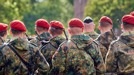 Eine Gruppe von Soldaten der Deutschen Bundeswehr in Tarnuniformen stehen in Formation mit Gewehr Bewaffnet bei einem Militär Appell © picture alliance / CHROMORANGE | Michael Bihlmayer 