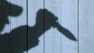 Eine Silhouette eines Mannes mit einem Messer vor einer Holzwand. © fotolia.com Foto: Alex