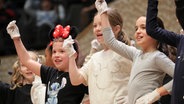 Konzertszene aus einem Discover-Music-Konzert: Verkleidete Kinder mit Handschuhen und Minnie-Maus-Ohren gestikulieren auf der Bühne © NDR Foto: Marcus Krüger