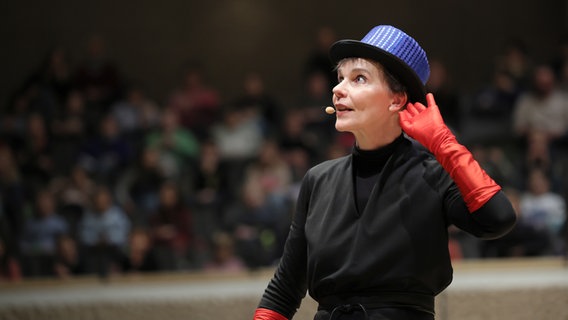 Konzertszene aus einem Schulkonzert: Christina Dean mit Glitzerzylinder und roten Handschuhen auf der Bühne der Elbphilharmonie © NDR Foto: Marcus Krüger