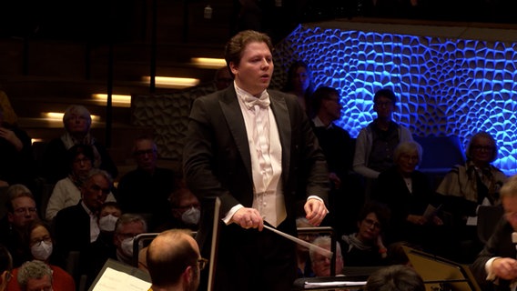 Screenshot: Dirigent Aivis Greters im Konzert mit dem NDR Elbphilharmonie Orchester in der Elbphilharmonie Hamburg im März 2023. © NDR Foto: Screenshot