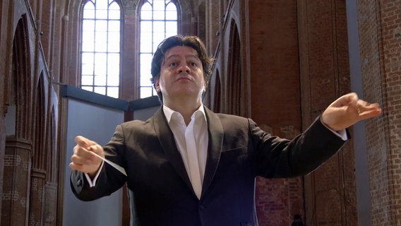 Konzertszene: Dirigent Cristian Măcelaru bei der Eröffnung der Festspiele MV 2024 in der Wismarer St.-Georgen-Kirche © NDR Foto: Screenshot