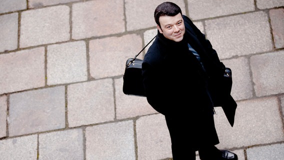 Violinist Vadim Gluzman mit Geigenkoffer auf Pflastersteinen. © Marco Borggreve Foto: Marco Borggreve