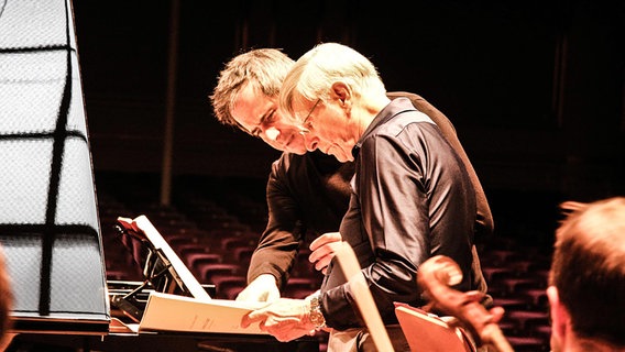 Piotr Anderszewski und Herbert Blomstedt stehen über eine Partitur gebeugt an einem Konzertflügel. © NDR 