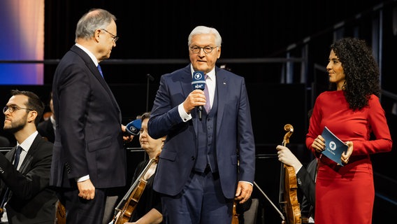 Frank-Walter Steinmeier mit einem Mikrofon in der Hand - links von ihm Niedersachsens Ministerpräsident Stephan Weil, zu seiner Rechten Moderatorin Siham El Maimouni. © NDR Foto: Helge Krückeberg