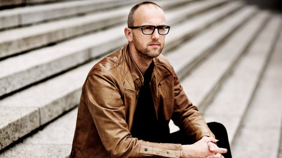 Dirigent Peter Djikstra sitzt auf einer Treppe. © Astrid Ackermann 