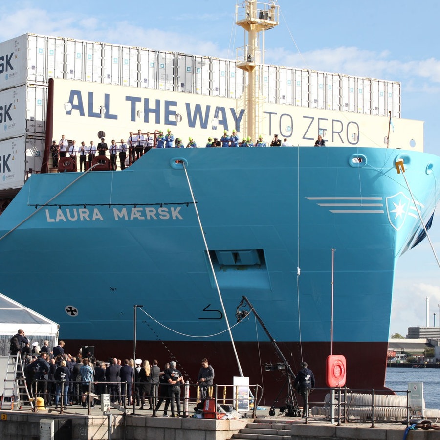 Eine Champagnerflasche zerschellt am Rumpf des weltweit ersten mit grünem Methanol betriebenen Containerschiff. © picture alliance/dpa Foto: Steffen Trumpf