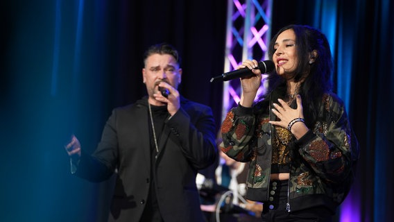 Sebastian Hämer und Carina Castillo sing den Abschlusstitel zusammen auf der Bühne. © NDR Foto: Jan-Philipp Baumgart