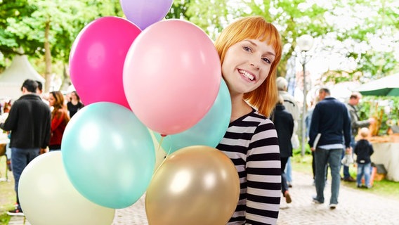 Junge Frau hält einen Strauß bunter Luftballons © Fotolia.com, NDR Foto: contrastwerkstatt