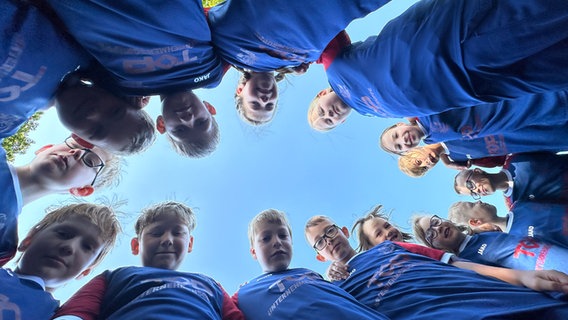 Kinder der Jugendfeuerwehr Barth stehen im Kreis und blicken herunter in die Kamera. © NDR Foto: Mathias Marius Krüger