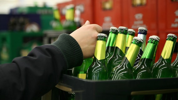 Eine Hand stellt eine Flasche Bier in einen Kasten. © Fotolia Foto: stokkete