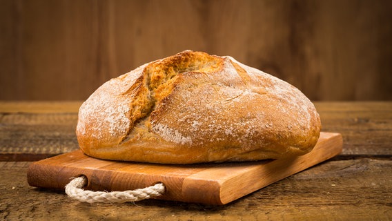 Ein frisch gebackenes Brot mit schöner Kruste liegt auf einem Holzbrett. © Colourbox Foto: Roman Tsubin