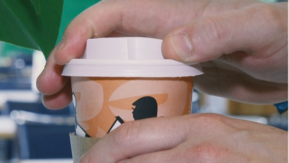 Eine Hand setzt einen Plastikdeckel auf einen Einweg-Kaffeebecher © NDR 