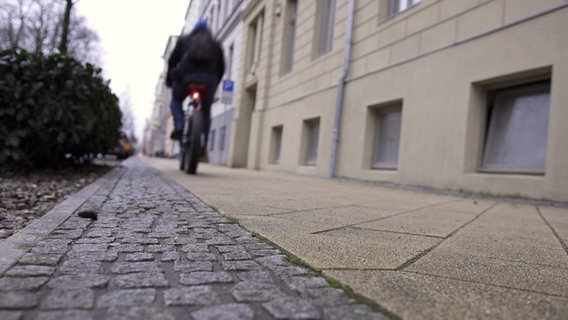 Ein Raadfahrer in den Rückenansicht fährt einen Gehweg entlang © ndr.de Foto: Udo Tanske