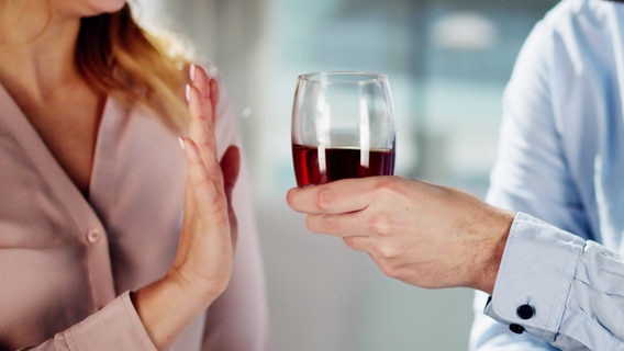 Eine Frau hebt ablehnend die Hand, als ihr ein Glas Wein angeboten wird. © IMAGO / Panthermedia 