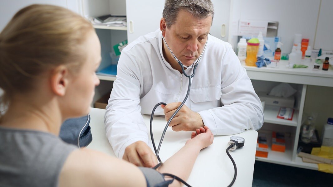 Arzt misst den Blutdruck einer jungen Patientin
