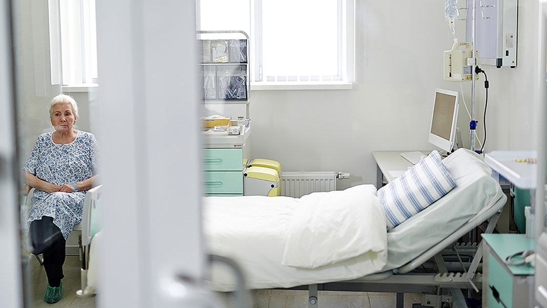 Patientin sitzt einsam am Krankenbett.