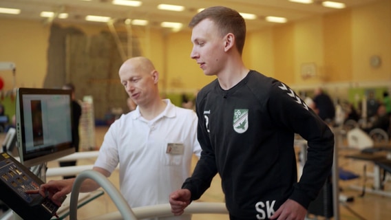 Bewegungs-Doc Helge Riepenhof steht neben seinem Patienten auf dem Laufband und erklärt, worauf es ankommt. © NDR 