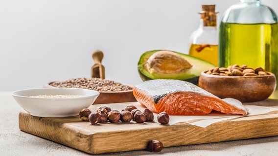 Avocado, salmon, nuts and oils on a wooden board © Colourbox 