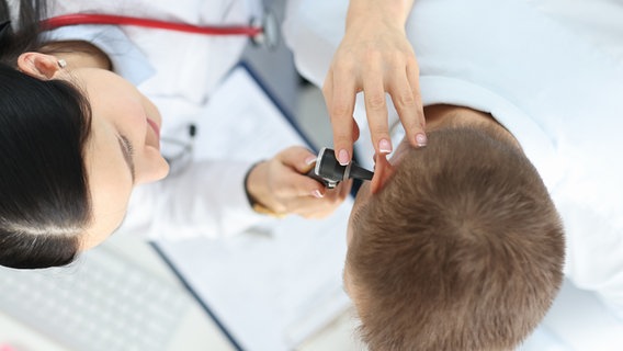 Ein Arzt untersucht mit einem speziellen Gerät das Ohr eines Patienten. © Colourbox Foto: Andrey Popov