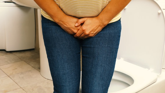 Frau auf Toilette hält sich Hände vor Geschlecht und presst die Beine zusammen (Bild: colourbox.de/AtlasStudio) © colourbox.de/AtlasStudio 