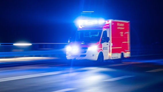 Rettungswagen mit Blaulicht bei Nacht auf regennasser Straße. Bewegungsunschärfe unterstreicht Geschwindigkeit. © picture-alliance/dpa | Marcel Kusch Foto: Marcel Kusch