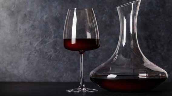 Ein Glas Rotwein steht neben einem Dekanter © Colourbox Foto: Evgeny Karandaev