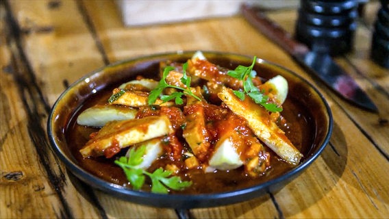 Smoked tofu in tomato sauce served on a plate.  © NDR 