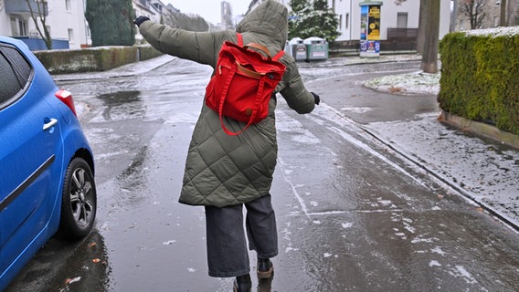 Eine Frau rutscht auf einer glatten Straße aus. © picture alliance/dpa Foto: Uwe Zucchi